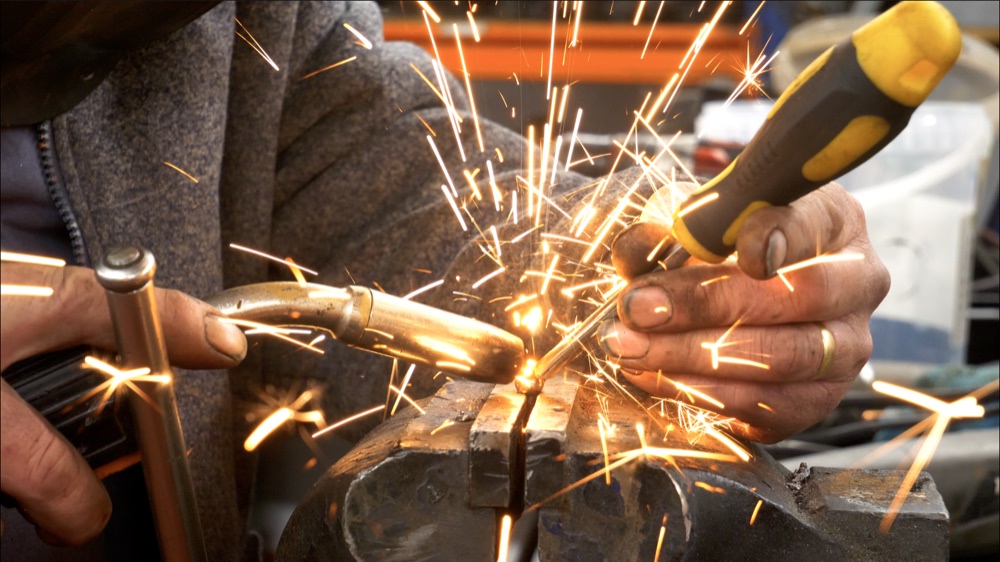 Hands carrying out metalwork with sparks flying